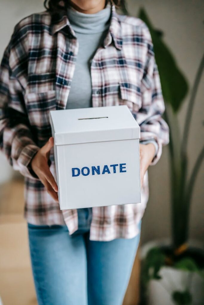 pexels photo 6347730 Crop unrecognizable woman in casual clothes standing with box for donations in hands on light room